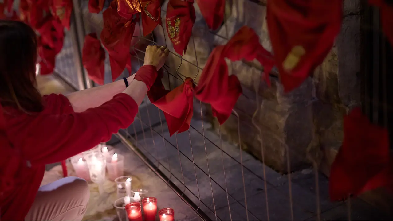 Cientos de personas depositan sus velas y pañuelos frente a la Iglesia de San Lorenzo momentos después del Pobre de mí con el que finalizan los nueve días de las Fiestas de San Fermín 2025. IÑIGO ALZUGARAY