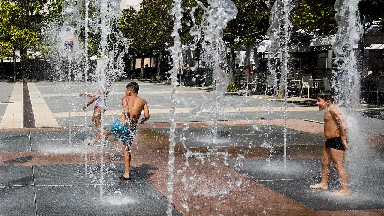 Niños y niñas juegan en la fuente de los chorros de Yamaguchi de Pamplona durante la de calor de Agosto de 2025. IÑIGO ALZUGARAY