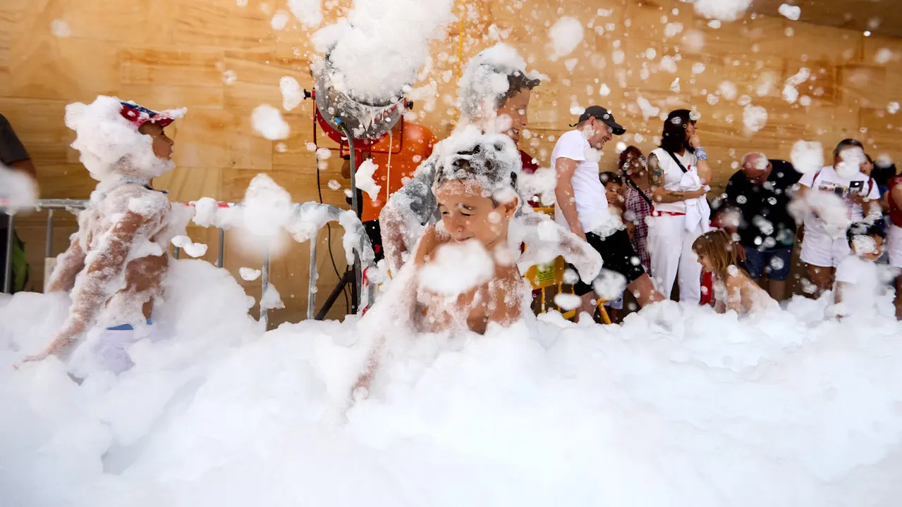 Niños y niñas juegan en la fiesta de la espuma tras el chupinazo de inicio de las Fiestas de Burlada 2025. IÑIGO ALZUGARAY