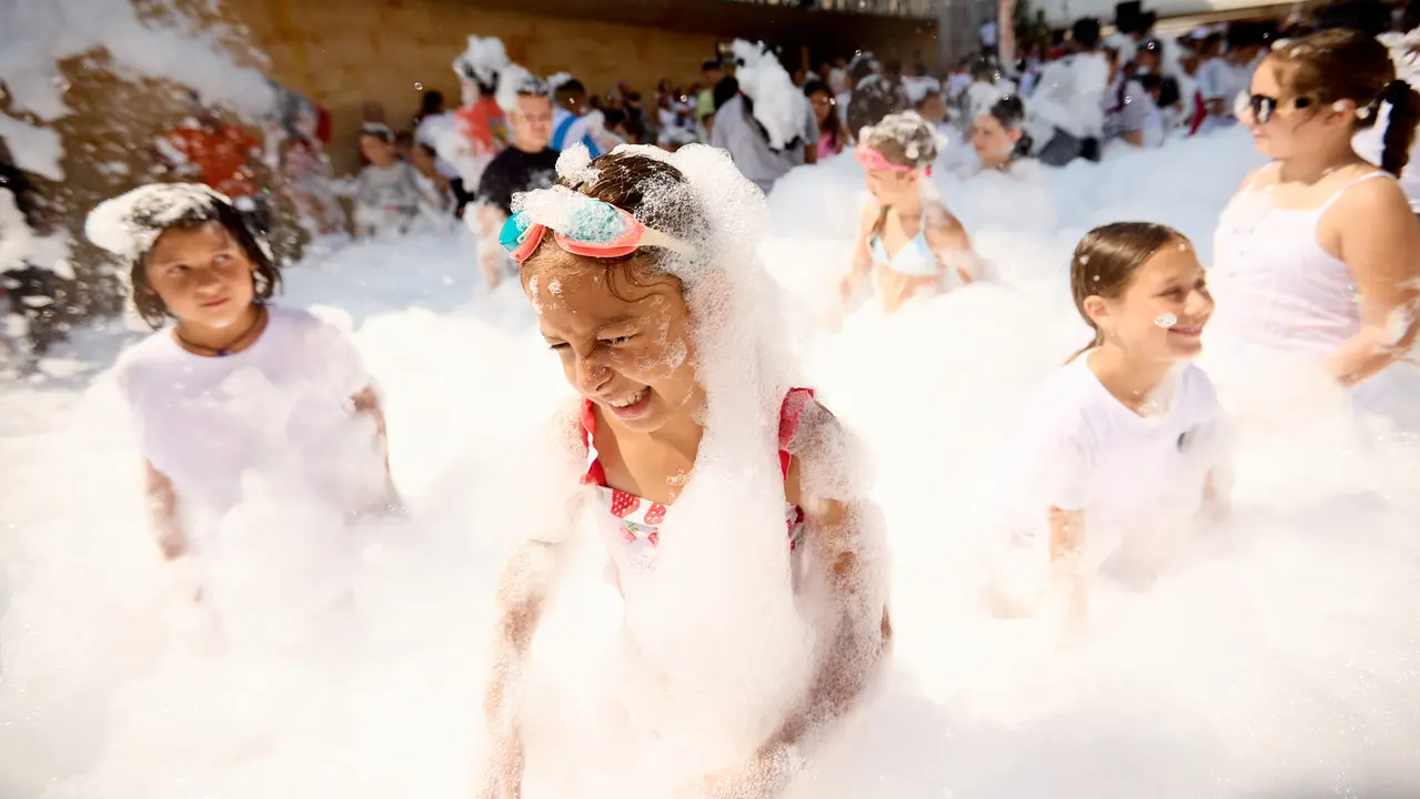 Niños y niñas juegan en la fiesta de la espuma tras el chupinazo de inicio de las Fiestas de Burlada 2025. IÑIGO ALZUGARAY
