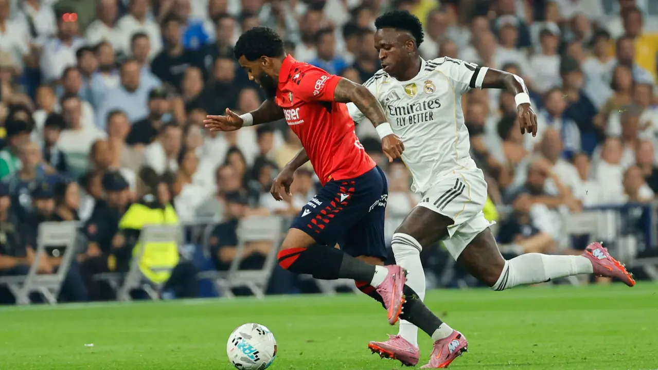 El delantero brasileño del Real Madrid Vinicius Jr. (d) persigue a Flavien-Enzo Boyomo, de Osasuna, durante el partido de la primera jornada de LaLiga que Real Madrid y Atlético Osasuna disputan hoy martes en el estadio Santiago Bernabéu. EFE/Mariscal