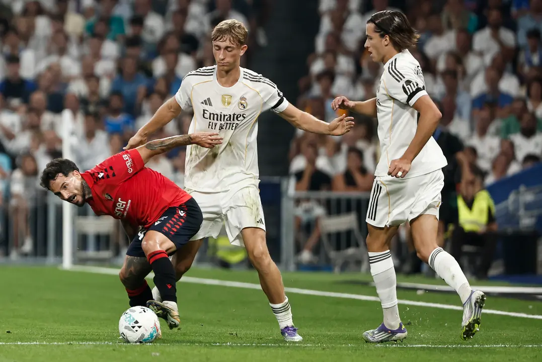 El defensa neerlandés del Real Madrid Dean Huijsen (c) lucha con Rubén García (i), de Osasuna, durante el partido de la primera jornada de LaLiga que Real Madrid y Atlético Osasuna disputan hoy martes en el estadio Santiago Bernabéu. EFE/SERGIO PÉREZ