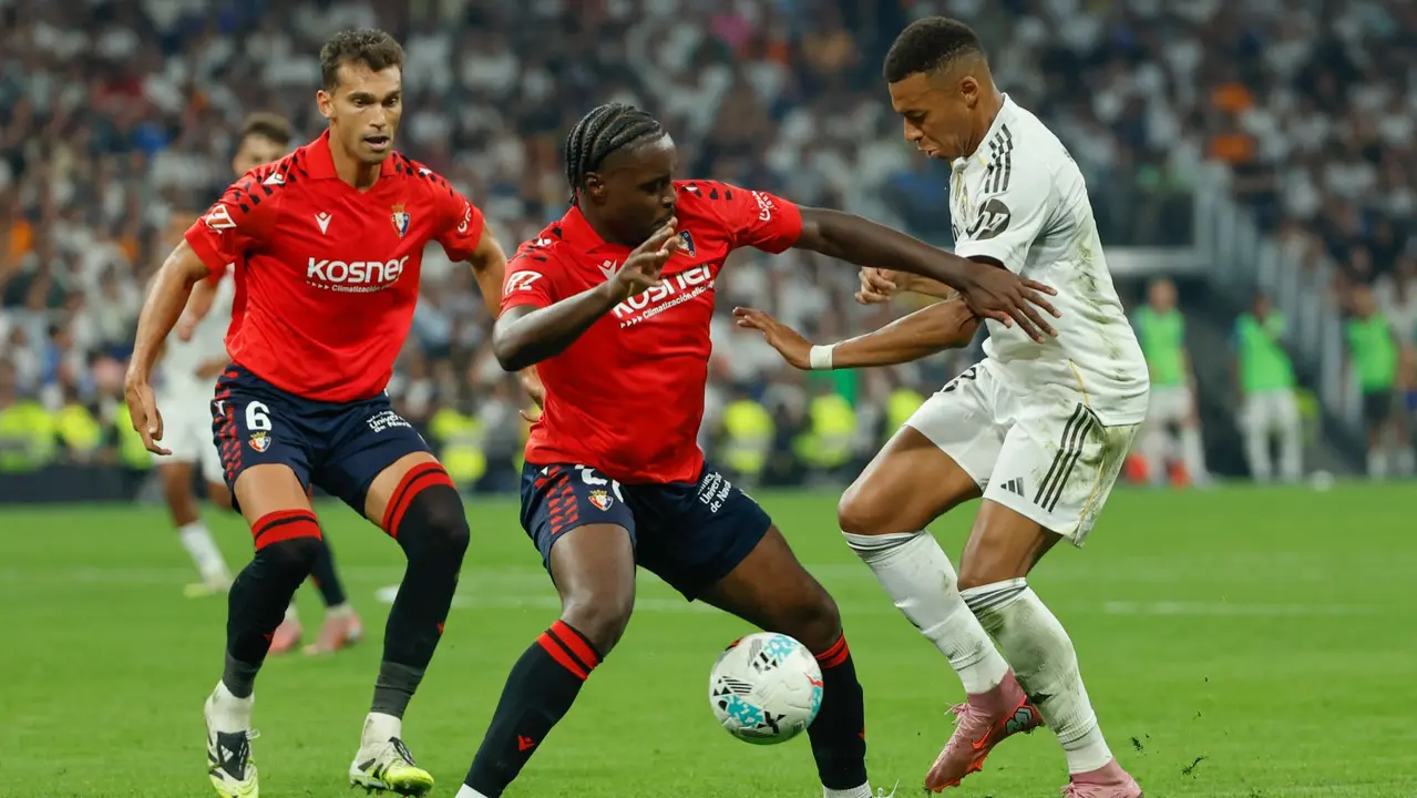 El delantero francés del Real Madrid Kylian Mbappé (d) lucha con Flavien-Enzo Boyomo (c), de Osasuna, durante el partido de la primera jornada de LaLiga que Real Madrid y Atlético Osasuna disputan hoy martes en el estadio Santiago Bernabéu. EFE/Mariscal