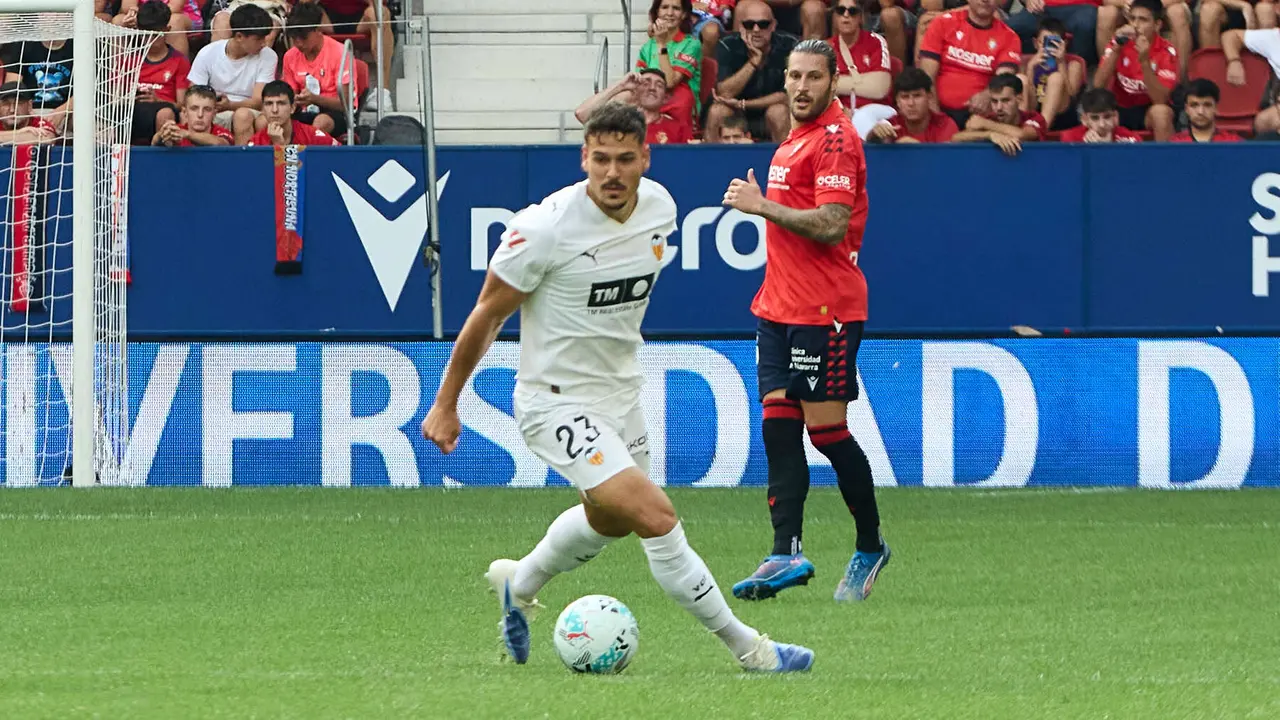 Filip Ugrinic (23. Valencia CF) y Juan Cruz (3. CA Osasuna) durante el partido de La Liga EA Sports entre CA Osasuna y Valencia CF disputado en el estadio de El Sadar en Pamplona. IÑIGO ALZUGARAY