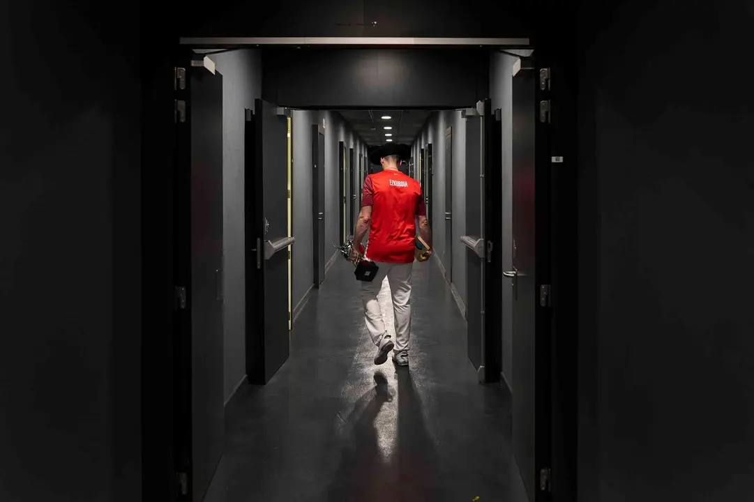 El pelotari Joseba Ezkurdia en el pasillo de los vestuarios del Navarra Arena, tras ganar la txapela del campeonato de parejas el 30 de marzo del 2025. Sujeta en la mano izquierda la copa de campe&oacute;n; en la derecha, el premio al mejor pelotari del Campeonato de Parejas. En la cabeza, la txapela de campe&oacute;n. MIGUEL OS&Eacute;S / DIARIO DE NAVARRA