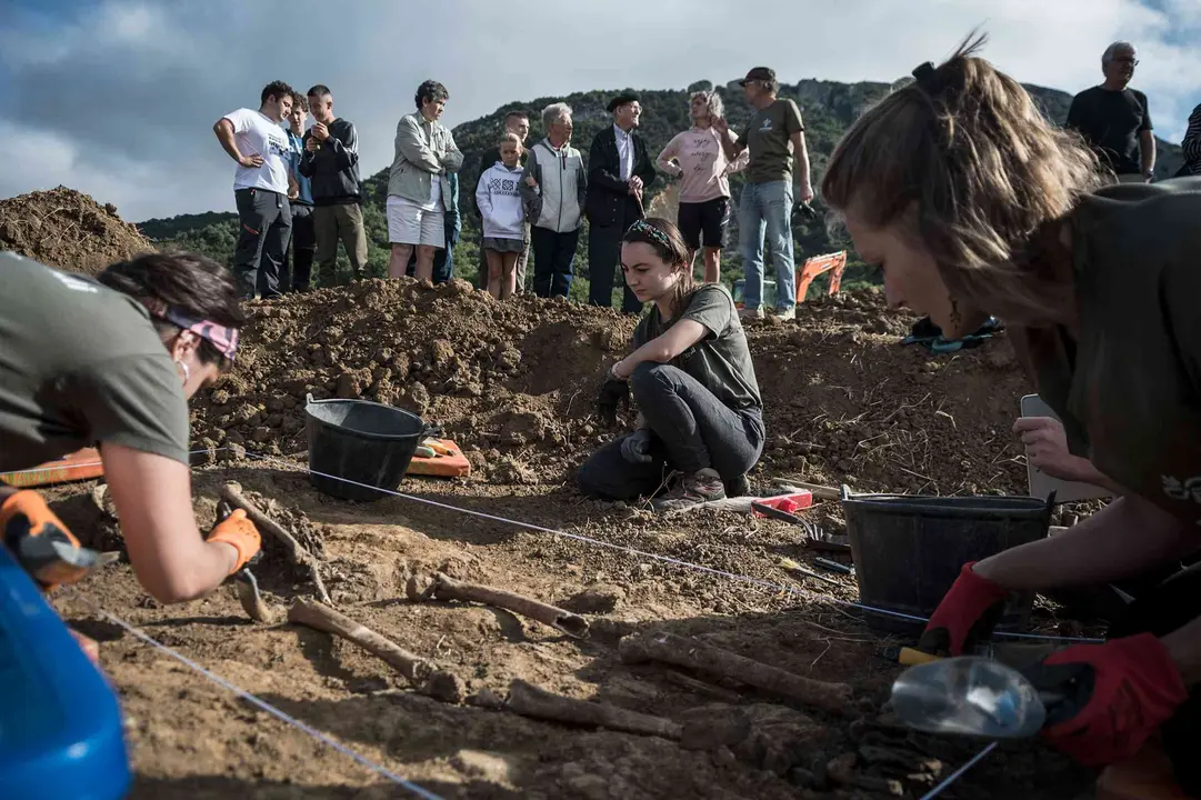 31 de julio de 2025. &ldquo;&Eacute;ramos unos cr&iacute;os. Varios vecinos enterraron unos cuerpos en este campo. Mi hermano Lucio y yo record&aacute;bamos que, de j&oacute;venes, el d&iacute;a 9 de mayo sub&iacute;amos en romer&iacute;a a la ermita de Santa Cruz, en Sarbil. Desde all&iacute; ve&iacute;amos que, en el campo, el cultivo crec&iacute;a de forma diferente. Ah&iacute; es donde los enterraron cuando yo ten&iacute;a 6 a&ntilde;os&rdquo;, expresa Domingo Zabalza Andueza, vecino de Muni&aacute;in de Gues&aacute;laz de 95 a&ntilde;os. Las voluntarias Edurne Turrillas, Naroa Carrasco, Amaia Kowasch y Haizea Senar y los miembros de la Sociedad de Ciencias Aranzadi, Lartaun P&eacute;rez y Tito Agirre, realizan los trabajos de exhumaci&oacute;n de uno de los asesinados -Ram&oacute;n Bengaray y Dionisio Guti&eacute;rrez, identificados este pasado diciembre- enterrados en las fosas de Muni&aacute;in d e Gues&aacute;laz. Gracias al Plan de Exhumaciones del Instituto Navarro de la Memoria del Ejecutivo Foral y a los avances en identificaci&oacute;n gen&eacute;tica, en los &uacute;ltimos a&ntilde;os, se ha logrado determinar certeramente los restos exhumados, en un 30% de los casos. 3.526 personas fueron asesinadas o muertas en cautividad en Navarra, a ra&iacute;z del golpe de estado militar de 1936. Muchas de ellas fueron enterradas en cunetas y campos de forma clandestina. LUIS CARMONA