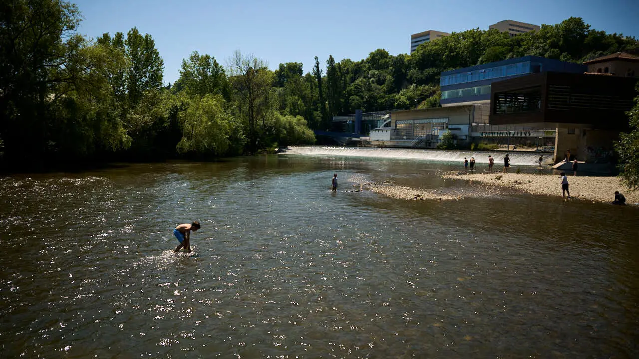 Decenas de personas aprovechan las altas temperaturas para refrescarse y disfrutar del r&iacute;o Arga a su paso por Pamplona. PABLO LASAOSA