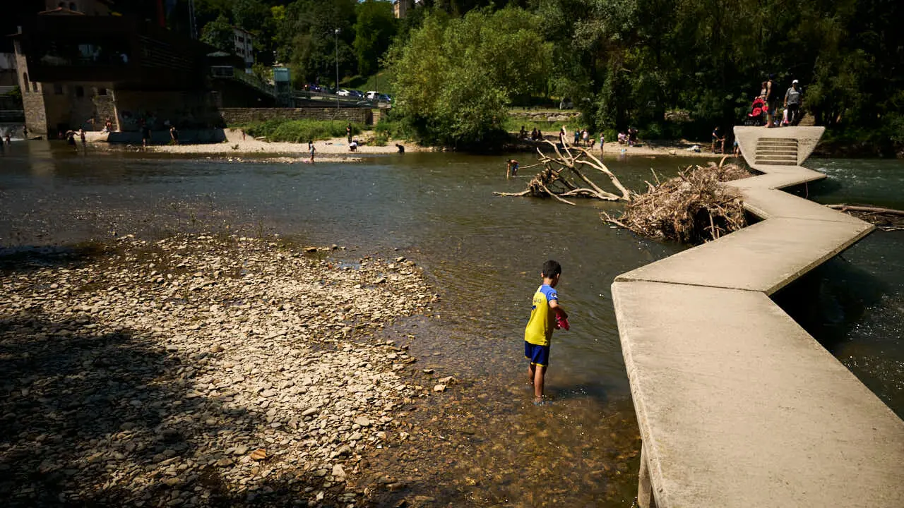 Decenas de personas aprovechan las altas temperaturas para refrescarse y disfrutar del r&iacute;o Arga a su paso por Pamplona. PABLO LASAOSA