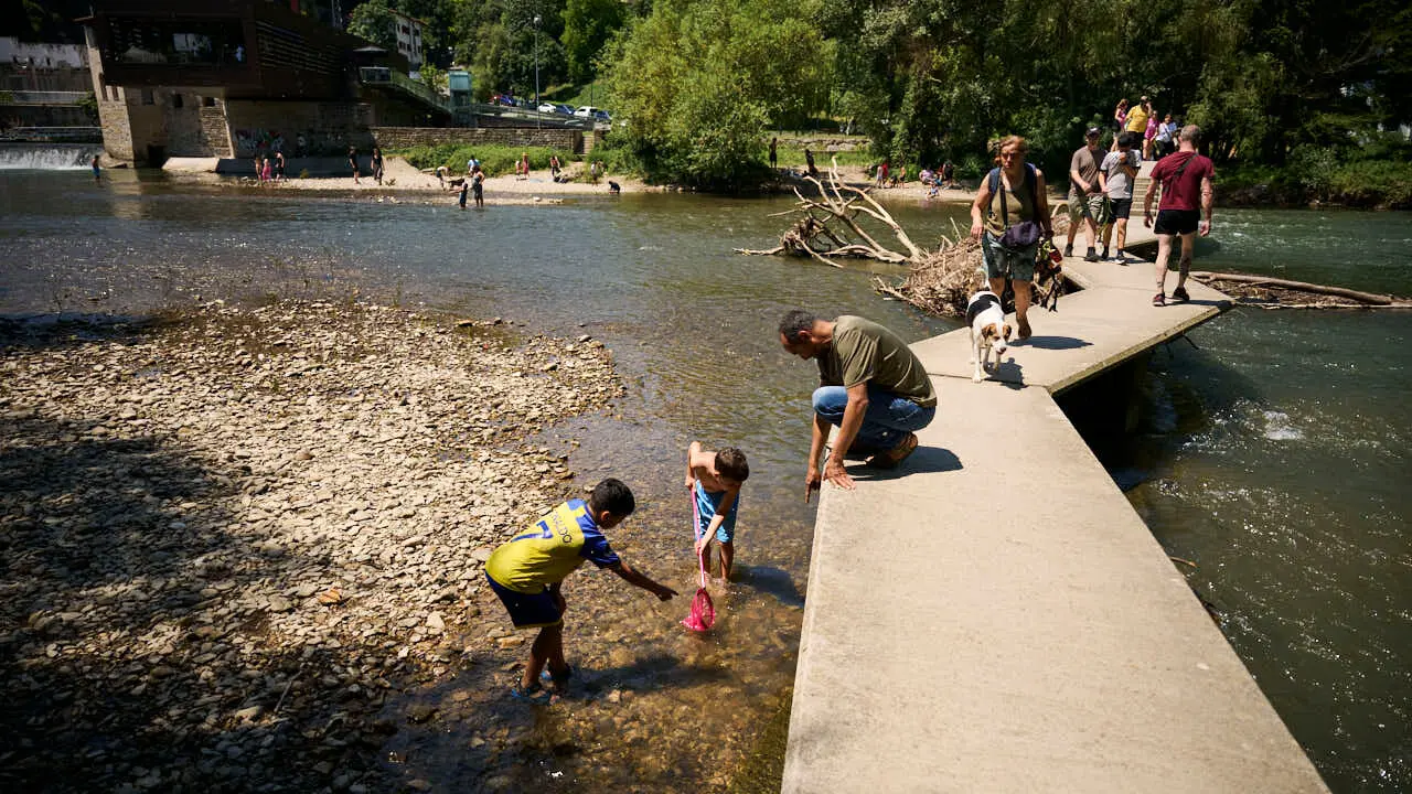 Decenas de personas aprovechan las altas temperaturas para refrescarse y disfrutar del r&iacute;o Arga a su paso por Pamplona. PABLO LASAOSA