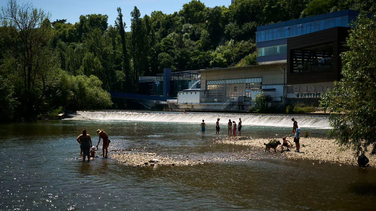 Decenas de personas aprovechan las altas temperaturas para refrescarse y disfrutar del r&iacute;o Arga a su paso por Pamplona. PABLO LASAOSA