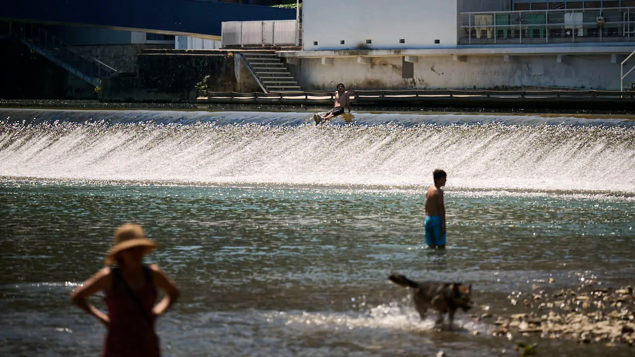 Decenas de personas aprovechan las altas temperaturas para refrescarse y disfrutar del r&iacute;o Arga a su paso por Pamplona. PABLO LASAOSA