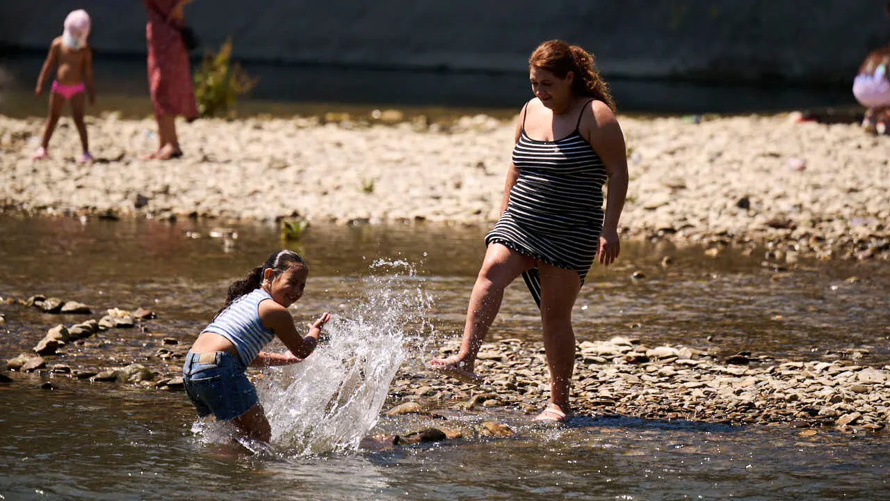 Decenas de personas aprovechan las altas temperaturas para refrescarse y disfrutar del r&iacute;o Arga a su paso por Pamplona. PABLO LASAOSA