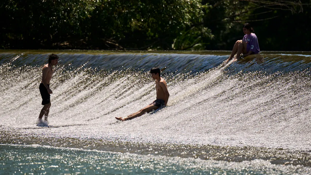 Decenas de personas aprovechan las altas temperaturas para refrescarse y disfrutar del r&iacute;o Arga a su paso por Pamplona. PABLO LASAOSA