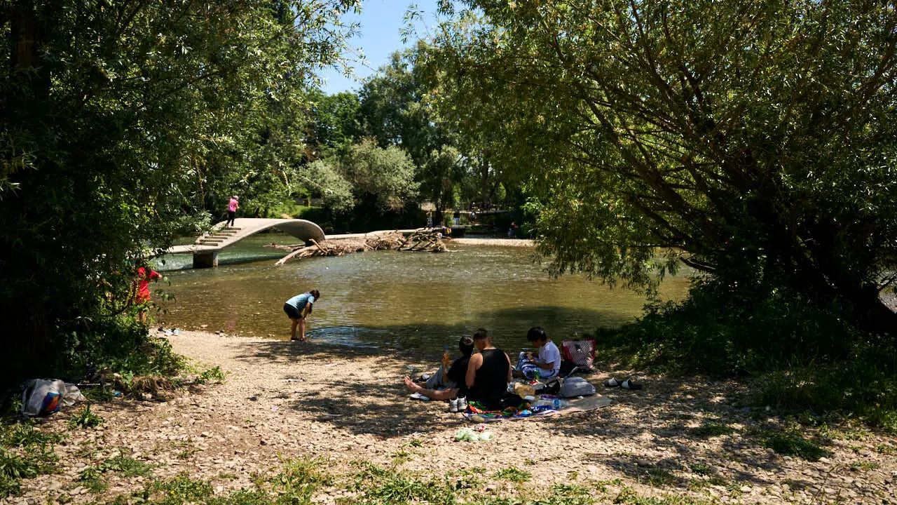 Decenas de personas aprovechan las altas temperaturas para refrescarse y disfrutar del r&iacute;o Arga a su paso por Pamplona. PABLO LASAOSA