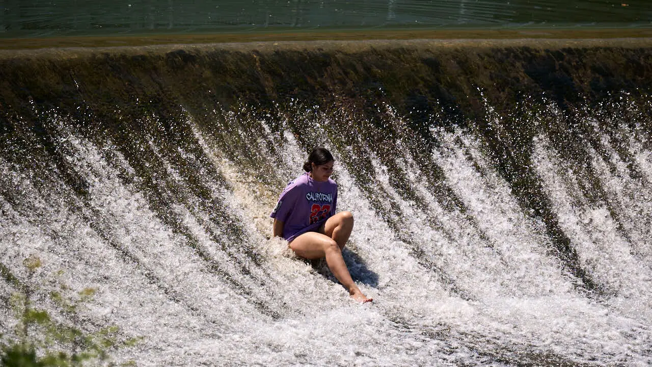 Decenas de personas aprovechan las altas temperaturas para refrescarse y disfrutar del r&iacute;o Arga a su paso por Pamplona. PABLO LASAOSA