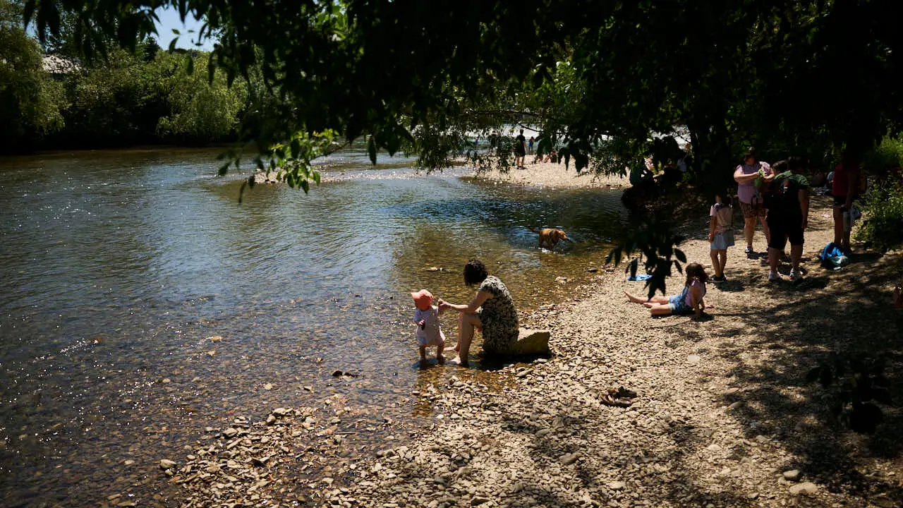 Decenas de personas aprovechan las altas temperaturas para refrescarse y disfrutar del r&iacute;o Arga a su paso por Pamplona. PABLO LASAOSA