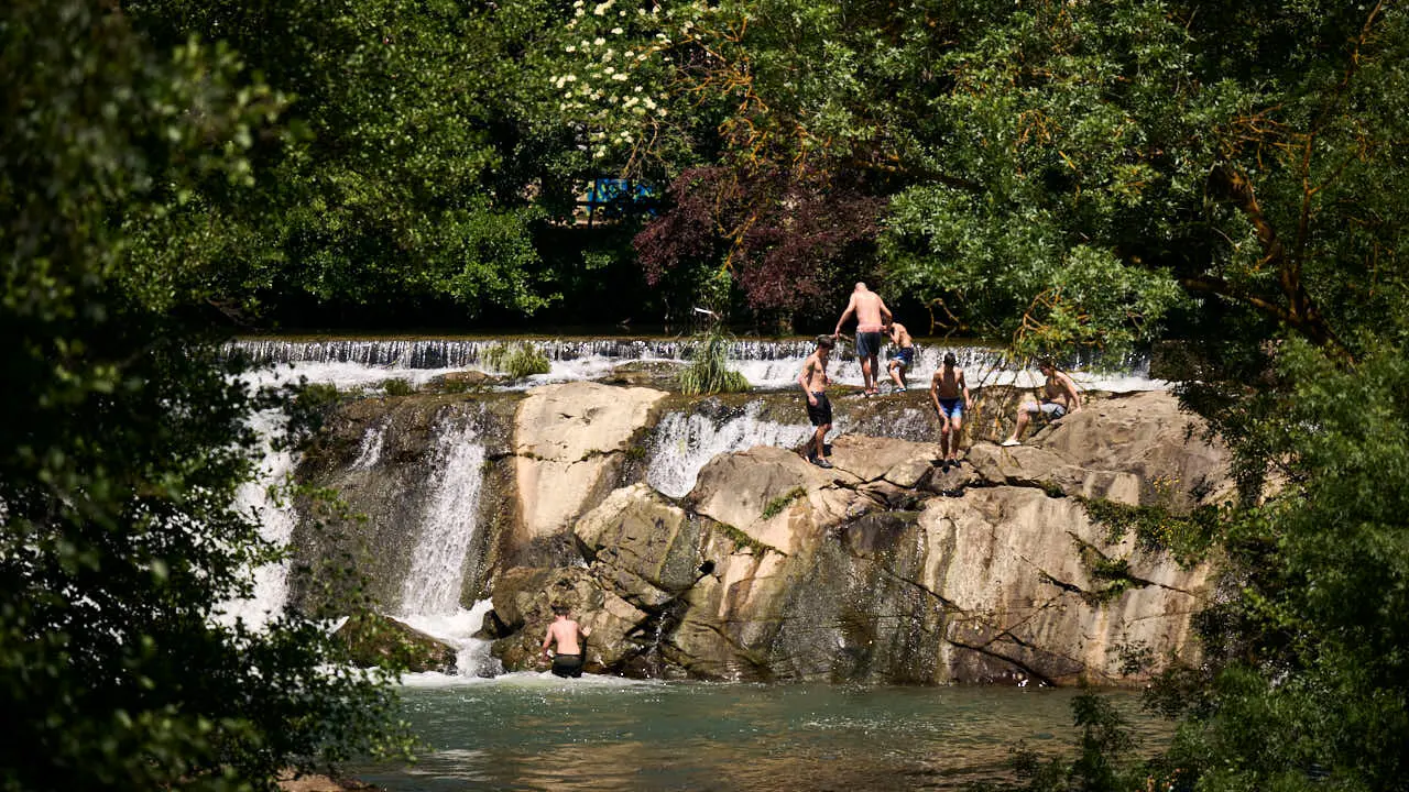 Decenas de personas aprovechan las altas temperaturas para refrescarse y disfrutar del r&iacute;o Arga a su paso por Pamplona. PABLO LASAOSA