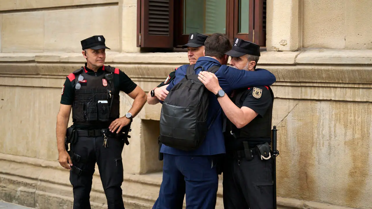 Una persona abraza a agentes de la Polic&iacute;a Foral durante el homenaje a los cinco polic&iacute;as forales fallecidos en un accidente de tr&aacute;fico. PABLO LASAOSA