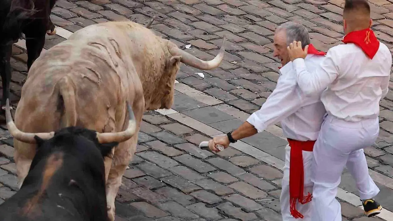PAMPLONA, 07/07/2026.- Dos mozos se apartan de los toros de la ganader&iacute;a Fuente Ymbro en el tramo final que desemboca en el callej&oacute;n de la Plaza de Toros en el primer encierro de los Sanfermines 2026 este martes en Pamplona. EFE/Villar Lopez