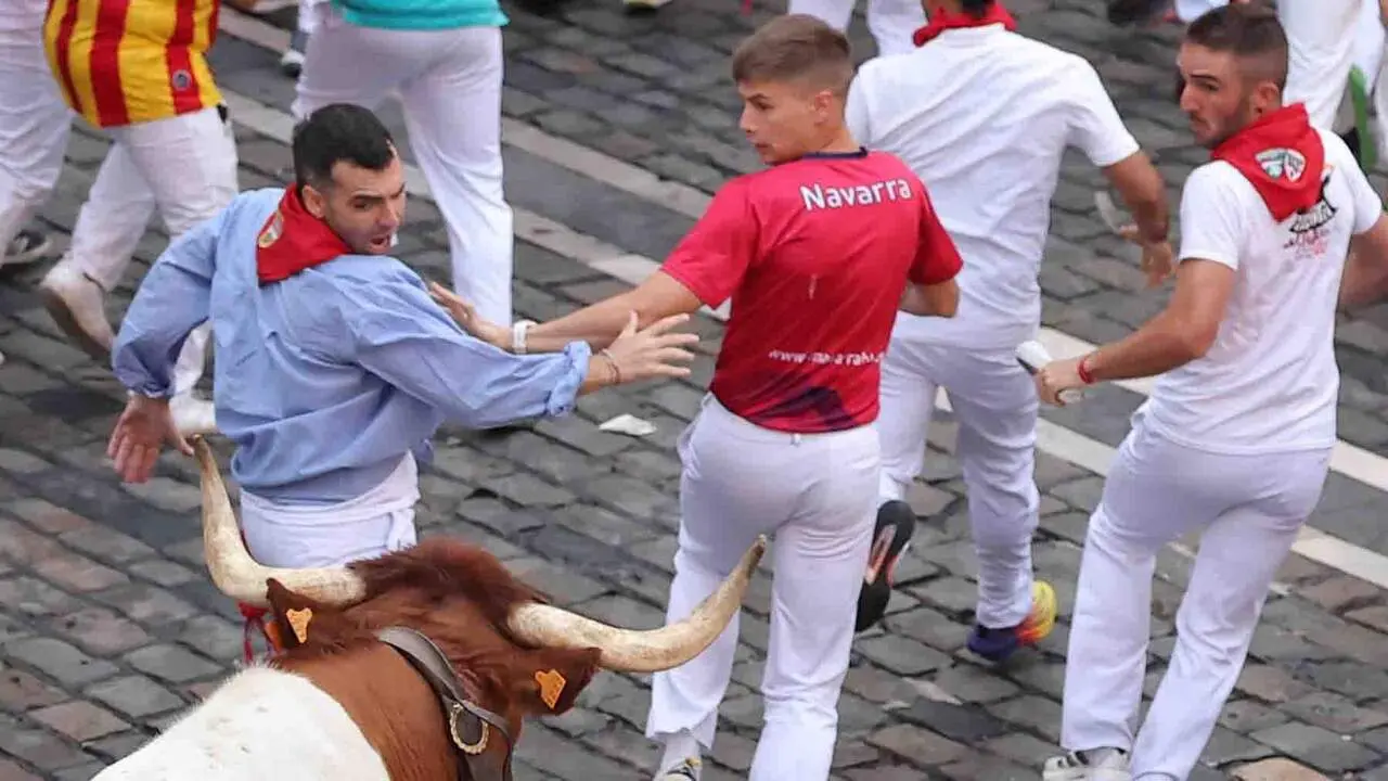 PAMPLONA, 09/07/2026.- Varios mozos realizan su carrera ante los toros de Victoriano del R&iacute;o a su paso por la Plaza Consistorial en el tercer encierro de los Sanfermines 2026, este jueves en Pamplona. EFE/J.P. Urdiroz