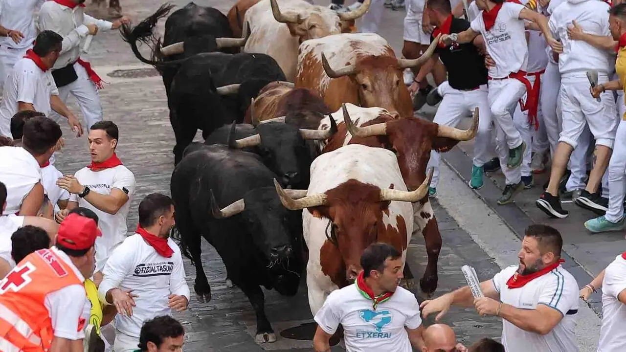 PAMPLONA, 09/07/2026.- Los mozos son perseguidos por los toros de Victoriano del R&iacute;o desde el final de la cuesta de Santo Domingo a la curva de Mercaderes, durante el tercer encierro de los Sanfermines, este jueves en Pamplona. EFE/ J.P. Urdiroz