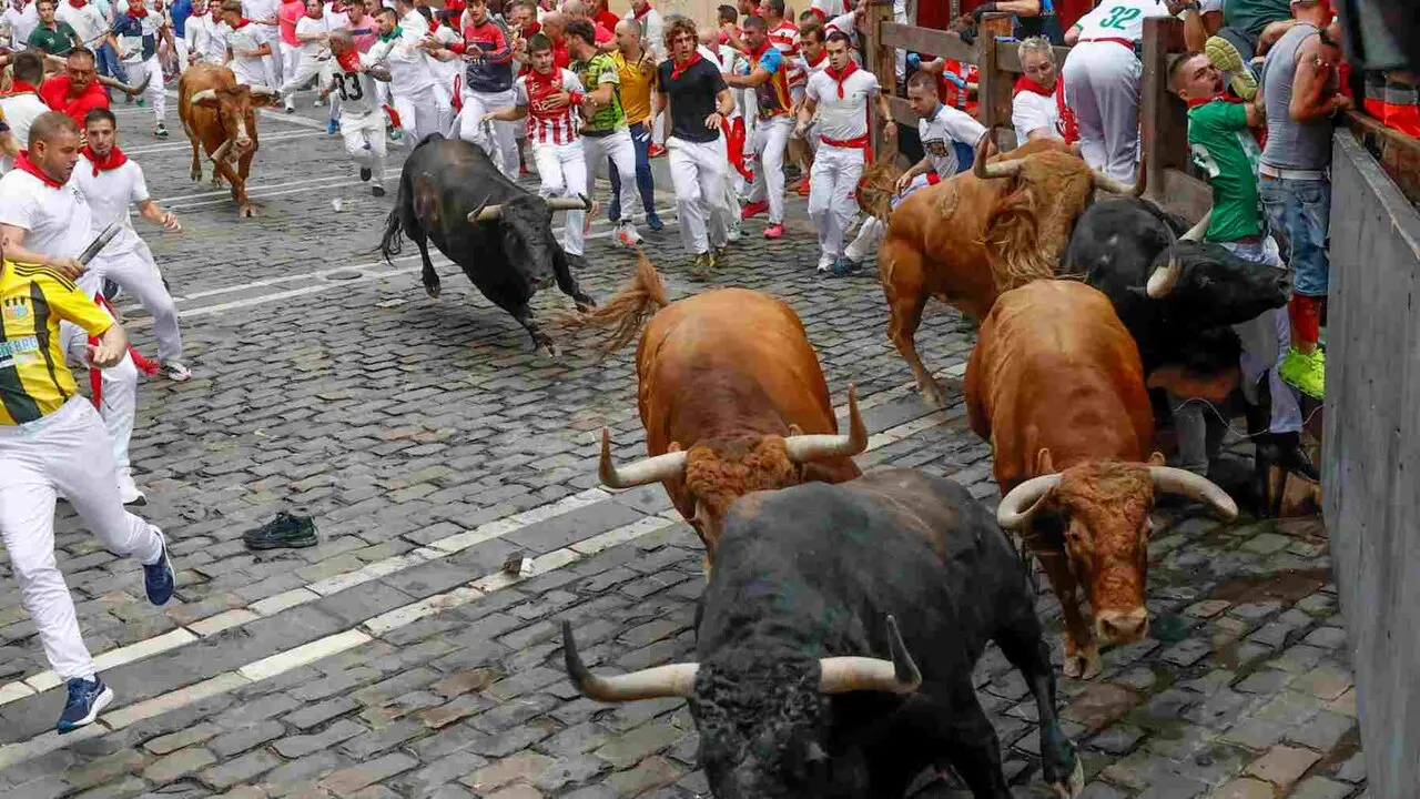 PAMPLONA, 10/07/2026.- Varios mozos, acorralados por los toros de la ganader&iacute;a de &Aacute;lvaro N&uacute;&ntilde;ez durante el cuarto encierro de los Sanfermines 2026 este viernes en Pamplona. EFE/Jesus Diges