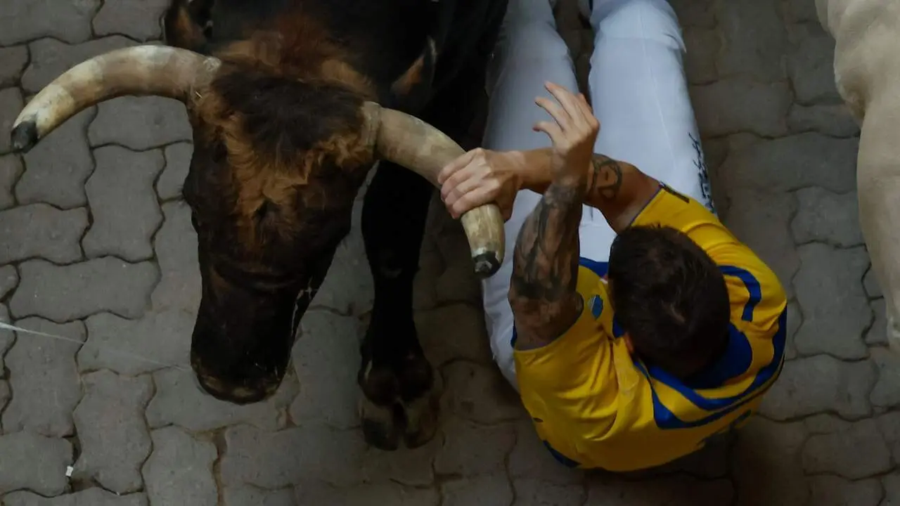 Mozo arrollado en la bajada al callej&oacute;n en el sexto encierro de San Ferm&iacute;n con toros de La Palmosilla. EFE / JES&Uacute;S DIGES
