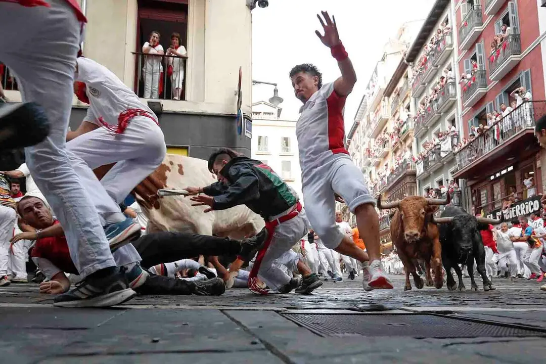 GRAFCAV6293. PAMPLONA, 12/07/2026.- Los toros de la ganader&iacute;a gaditana de La Palmosilla entran en la curva de Mercaderes durante el sexto encierro de los Sanfermines 2026, este domingo en Pamplona. EFE/ Villar L&oacute;pez