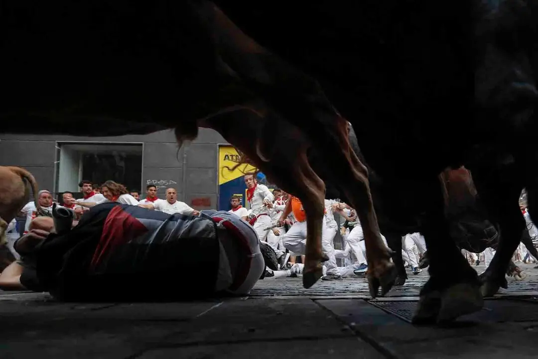 GRAFCAV6296. PAMPLONA, 12/07/2026.- Los toros de la ganader&iacute;a gaditana de La Palmosilla entran en la curva de Mercaderes durante el sexto encierro de los Sanfermines 2026, este domingo en Pamplona. EFE/ Villar L&oacute;pez
