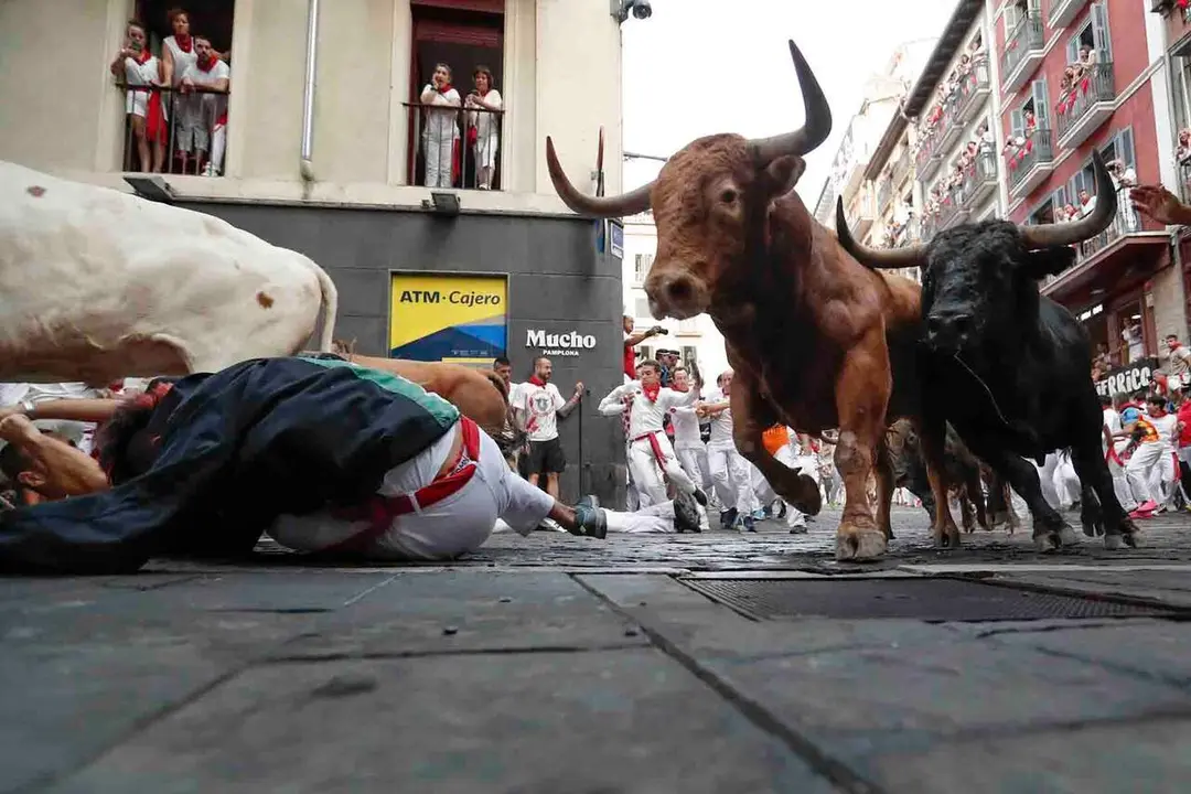 GRAFCAV6294. PAMPLONA, 12/07/2026.- Los toros de la ganader&iacute;a gaditana de La Palmosilla entran en la curva de Mercaderes durante el sexto encierro de los Sanfermines 2026, este domingo en Pamplona. EFE/ Villar L&oacute;pez