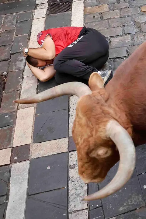 PAMPLONA, 12/07/2026.- Un toro de la ganader&iacute;a gaditana de La Palmosilla a su paso por la curva de Mercaderes durante el sexto encierro de los Sanfermines 2026, este domingo en Pamplona. EFE/Villar L&oacute;pez