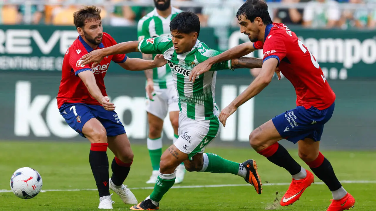 El delantero del Betis Cucho Hern&aacute;ndez (c) trata de escapar entre Alejandro Catena (d) y Jon Mocayola, ambos de Osasuna, durante el partido de LaLiga de f&uacute;tbol que Real Betis y CA Osasuna disputan este domingo en el estadio de La Cartuja, en Sevilla. EFE/Julio Mu&ntilde;oz.