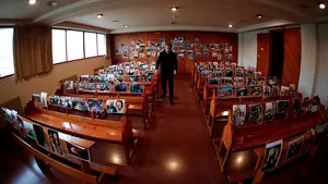El párroco de Santa María de Ermitagaña coloca fotos de sus feligreses en los bancos de la iglesia