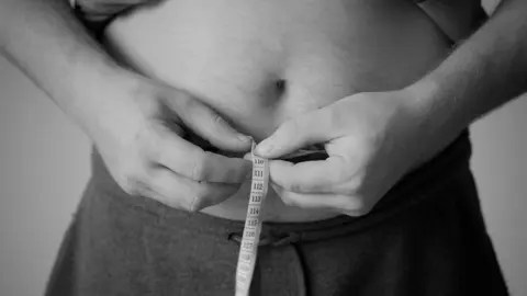 Una persona mide el contorno de su cintura.jpg