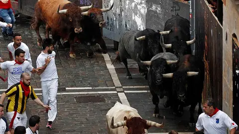 Los toros de la ganadería sevillana de Miura enfilan la calle Estafeta tras pasar la curva de Mercaderes durante el octavo y último encierro de los Sanfermines 2018, el más rápido de las fiestas con 2 minutos y 12 segundos de duración, en el que, según el primer parte médico, no hay heridos por asta. EFE/Villar López