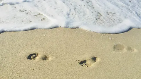 Pisadas en la rena a punto de ser borradas por la marea. Photo by Khadeeja Yasser on Unsplash