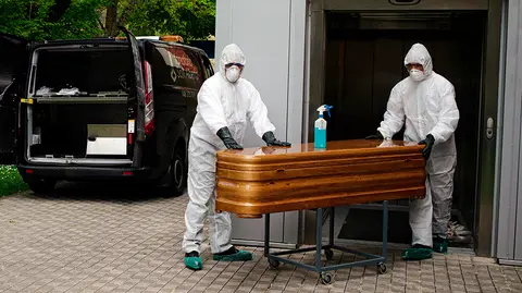 GRAFCAV4780. PAMPLONA, 22/04/2020.-  Trabajadores de un tanatorio de Pamplona sacan del Hospital de Navarra un ata&uacute;d para proceder a su desinfecci&oacute;n antes de trasladarlo al cementerio. La Asociaci&oacute;n Nacional de Servicios Funerarios (PANASEF) ha enviado a Navarra material de protecci&oacute;n frente al contagio por coronavirus para los trabajadores de los tanatorios existentes en la Comunidad foral que viven estos d&iacute;as "una calma tensa". Se han suministrado a las distintas empresas buzos, guantes, mascarillas, pantallas protectoras y geles hidroalcoh&oacute;licos en funci&oacute;n de las necesidades y la urgencia para intentar as&iacute; asegurar la salud de los trabajadores de los tanatorios, en especial de quienes deben recoger las cuerpos de las personas fallecidas y llevarlos hasta al lugar de entierro o incineraci&oacute;n. EFE/ I&ntilde;aki Porto
