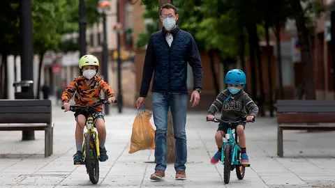HUESCA, 26/04/2020.- Unos niños en bicicleta pasean con su padre por la calle Fatás y la plaza Navarra de Huesca, este domingo, cuando se cumplen 43 días de confinamiento, a partir del que más de seis millones de niños menores de 14 años pueden salir a la calle una hora al día, acompañados de un adulto y a un kilómetro como máximo de sus casas. EFE/ Javier Blasco
