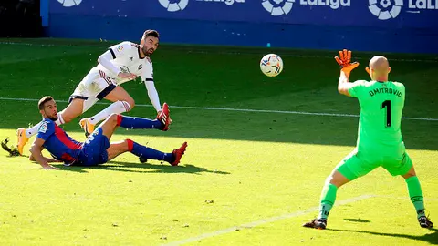 GRAF2814. &Eacute;IBAR, 18/10/2020.- El delantero del Osasuna Enric Gallego (c) remata ante el jugador de la SD Eibar Burgos, y el guardameta Dimitrovic, durante el encuentro de la sexta jornada de la Liga de Primera Divisi&oacute;n disputado este domingo en el estadio Ipurua en &Eacute;ibar. EFE/Gorka Estrada

