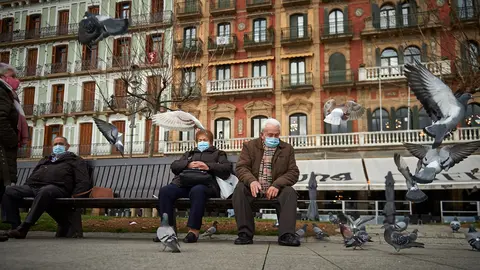 Dos personas dan de comer a las palomas en la Plaza del Castillo de Pamplona durante la pandemia de coronavirus. MIGUEL OS&Eacute;S