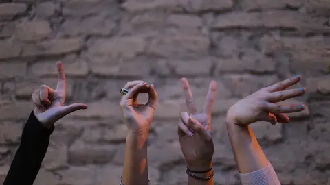 Varias personas utilizan el lenguaje de signos con las manos.