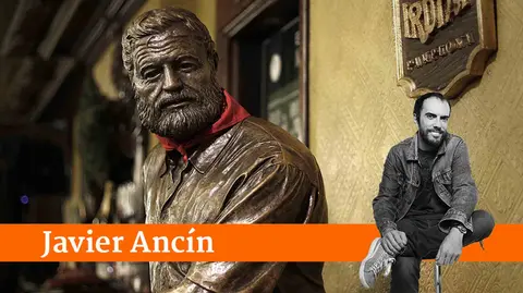 GRAF9791. PAMPLONA 01/12/2018.- La escultura de Ernest Hemingway luce el tradicional "pañuelico" de San Fermín en el popular Café Iruña de la Plaza del Castillo de Pamplona. Esta plaza acoge la exposición "Recuperando a Hemingway" donde se muestran algunas fotografías inéditas y se documentan visitas y rodajes, con imágenes de Henry Fonda, Orson Welles, Ava Gadner, Deborah Kerr, Gary Cooper, Henry Fonda, Lauren Bacall o Sean Connery por las calles de la capital navarra. El escritor estadounidense protagoniza por tercera edición consecutiva un ciclo de actividades turísticas este año centradas en su relación con el cine, y que pretende ofrecer la vertiente "más cultural" de la imagen que proyectó de la ciudad. EFE/Villar López