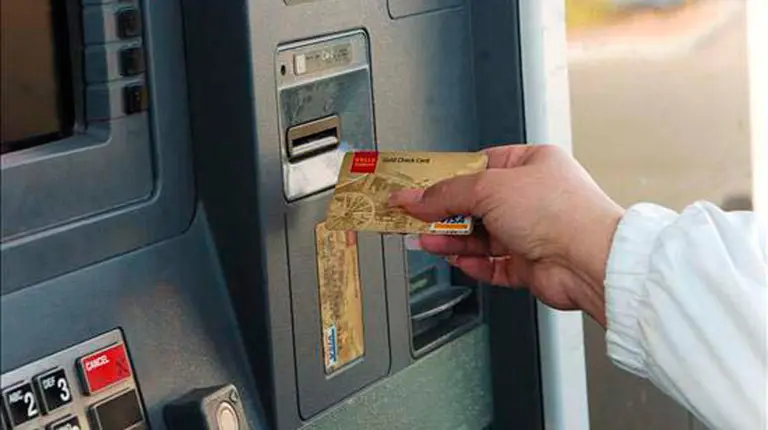 Un cliente saca dinero de un cajero. 