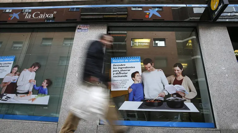 Un hombre pasa por delante de una oficina de Caixabank.