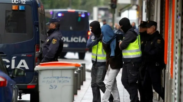 Dos efectivos de la Policía acompañan a una persona detenida. EFE.