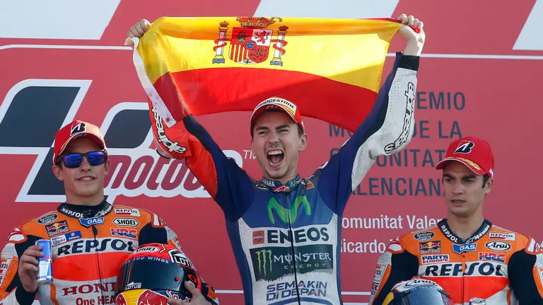 Jorge Lorenzo sujeta la bandera española en el pódium. Efe.