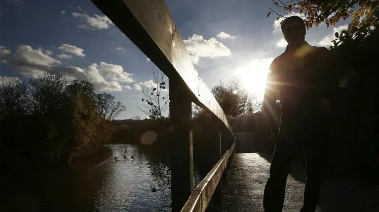 Una persona observa a varios piragüistas en el rio Arga a su paso por Pamplona. EFE. Jesus Diges