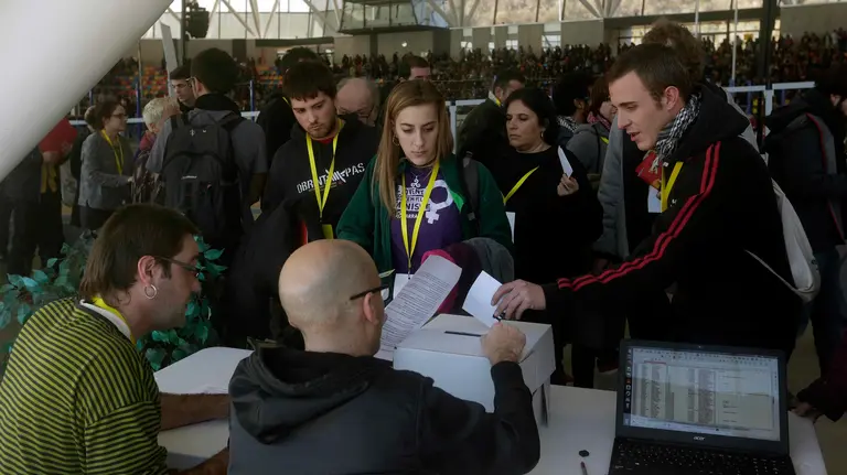Vista a través de un cristal de los participantes en la primera votación realizada durante la asamblea de la CUP sobre la investidura de Artur Mas como presidente de la Generalitat, tras más de tres horas de intenso y disputado debate, con una cincuentena de intervenciones a favor y en contra. EFE/Alberto Estévez