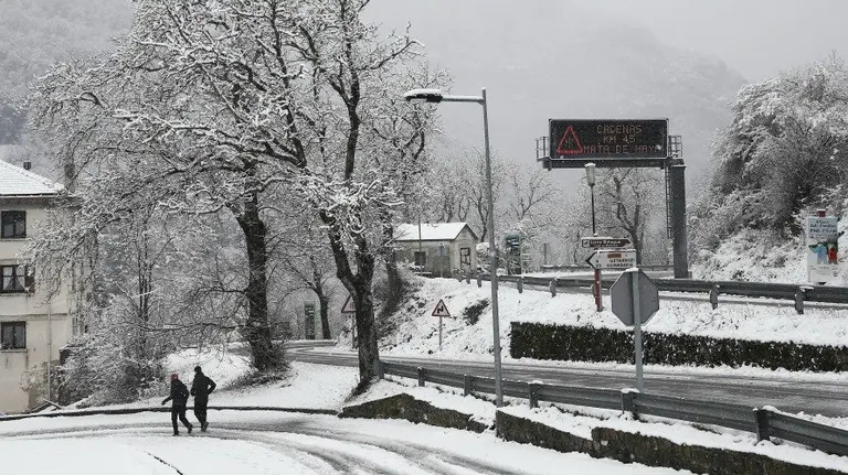 Dos personas pasean por la NA-137 junto a la localidad navarra de Isaba. Tiempo, nieve. EFE.