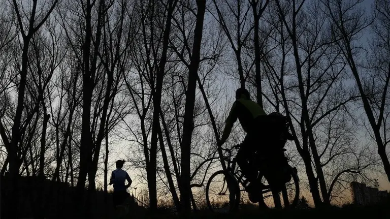 Tiempo, varias personas en la orilla del río Arga en el atardecer de Pamplona. EFE.